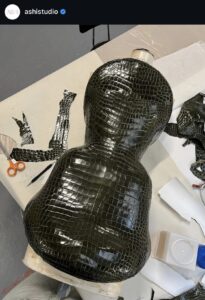 Atelier Instagram screenshot of a gasoline crocodile runway piece molded into curves.