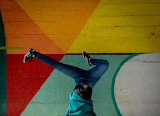 man in red shirt and blue denim jeans lying on concrete floor