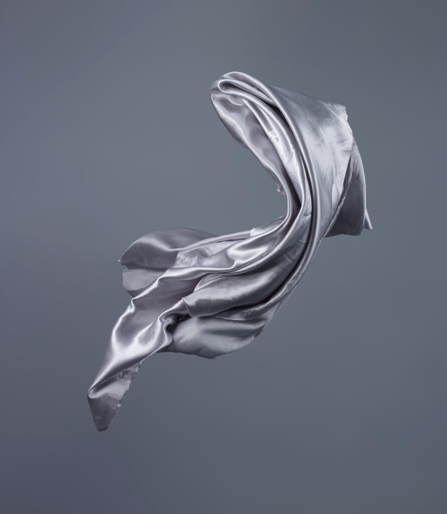 An image displaying the freeze-frame movement of a blue fabric, showcasing its dynamic contours and textures.