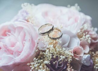 gold-colored bridal ring set on pink rose flower bouquet