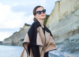 woman wearing black and brown dress and sunglasses standing near body of water under white and blue sky