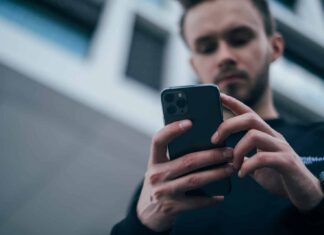 man wearing black sweater using smartphone
