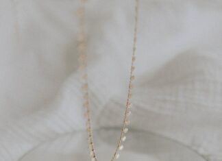 gold necklace on white textile