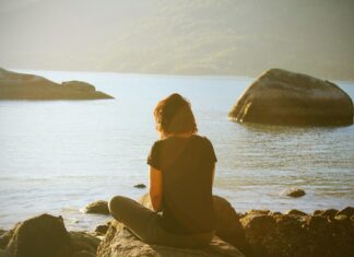 person sitting near body of water during daytime