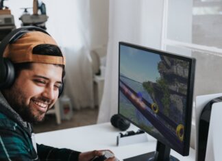 a man wearing headphones and sitting at a desk with a computer