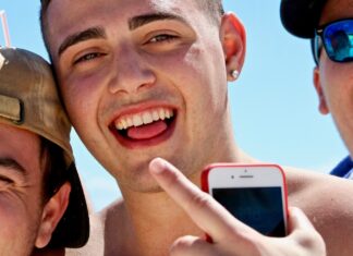 man holding iPhone in between two men