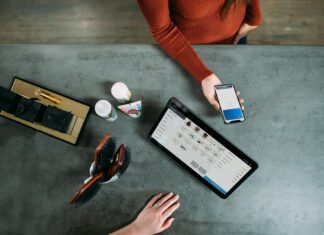 person holding smartphone beside tablet computer