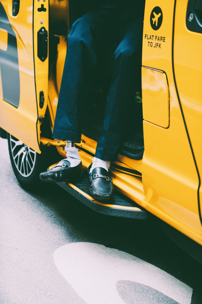A stylish man stepping out of a taxi marked 'Flat Fare to JFK'